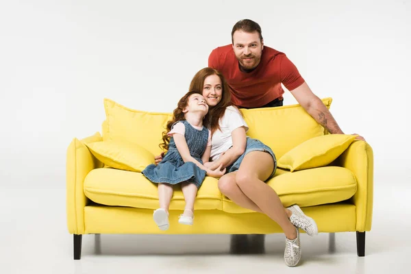 Mutter und Tochter auf dem Sofa, während der Vater isoliert auf weißem Hintergrund steht — Stockfoto