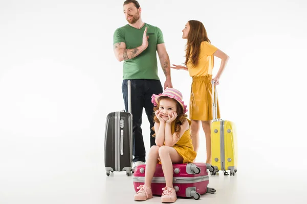 Criança perturbada sentada na mala, enquanto os pais discutem isolado no branco, conceito de viagem — Fotografia de Stock