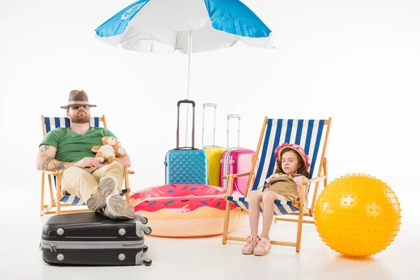 Padre e hija en sombreros durmiendo en tumbonas aisladas en blanco, concepto de viaje - foto de stock