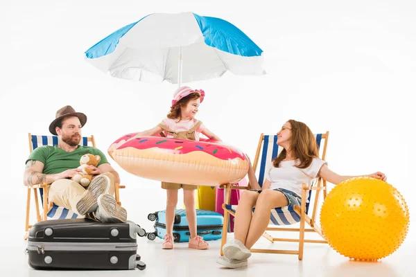 Joyeux petit enfant debout avec anneau de flottaison entre les parents assis sur des chaises longues isolées sur blanc, concept de voyage — Photo de stock