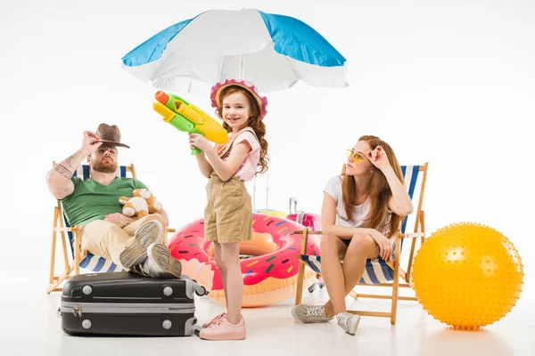 Family of tourists with sun loungers, sunshade, flotation ring and water gun isolated on white — Stock Photo