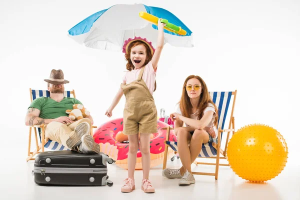 Père dormant dans des chaises longues tandis que la fille debout avec pistolet à eau près de la mère isolé sur blanc, concept de voyage — Photo de stock