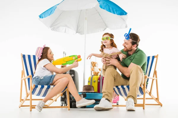 Père avec fille en lunettes de natation et mère avec pistolet à eau isolé sur blanc, concept de voyage — Photo de stock