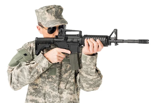 Guapo soldado del ejército con uniforme apuntando con arma aislada en blanco - foto de stock