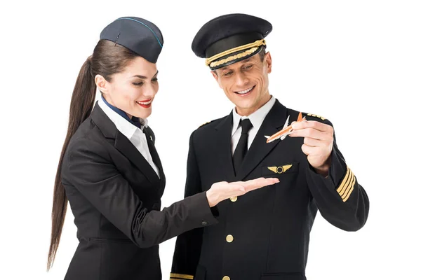Capitán de línea aérea y azafata sosteniendo avión de juguete aislado en blanco - foto de stock