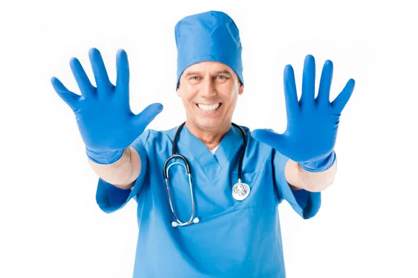 Médico sorridente mostrando as mãos em luvas de látex isolado em branco — Fotografia de Stock