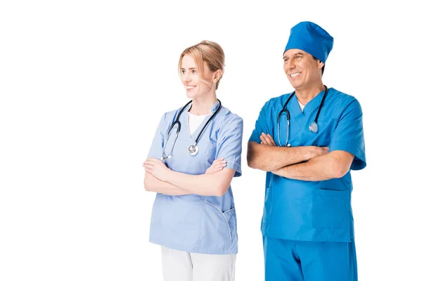 Médico y enfermera sonriente con estetoscopios de pie con los brazos cruzados aislados en blanco - foto de stock