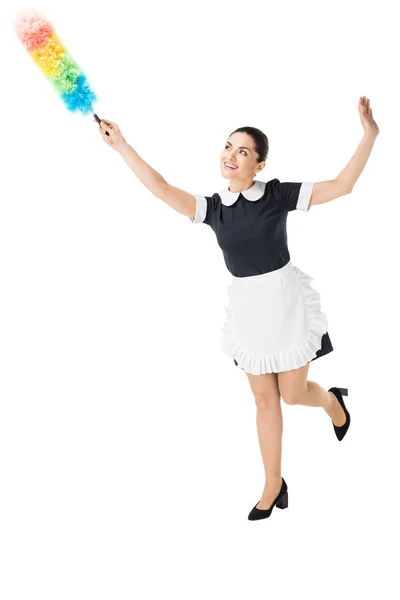 Young maid in professional uniform using colorful duster isolated on white — Stock Photo