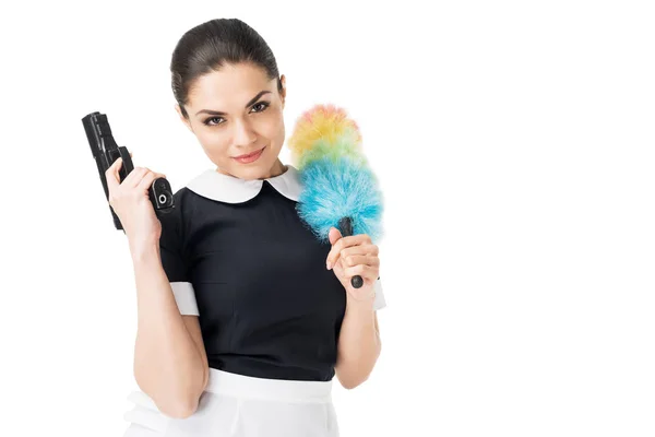 Brunette maid in professional uniform holding duster and gun isolated on white — Stock Photo