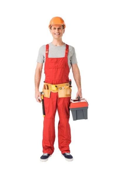 Smiling handyman in overalls holding toolbox isolated on white — Stock Photo