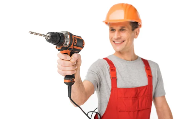 Smiling handyman in overalls holding drill isolated on white — Stock Photo