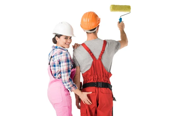Mulher no construtor uniforme tocando nádegas do homem com rolo de pintura isolado no branco — Fotografia de Stock