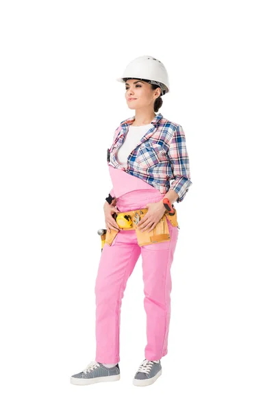 Приваблива жінка-будівельник в рожевій формі з поясом інструментів ізольовані на білому — стокове фото