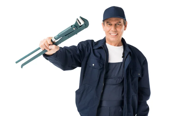 Cheerful plumber in uniform holding adjustable wrench isolated on white — Stock Photo