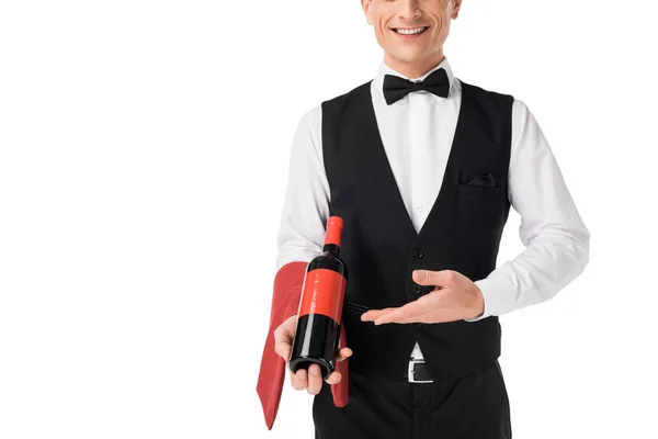 Smiling professional waiter presenting wine bottle isolated on white — Stock Photo