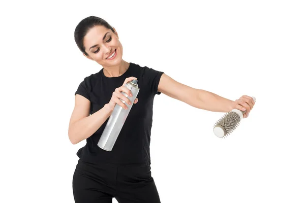 Cabeleireiro fêmea sorridente com spray de cabelo e escova de cabelo isolada em branco — Fotografia de Stock