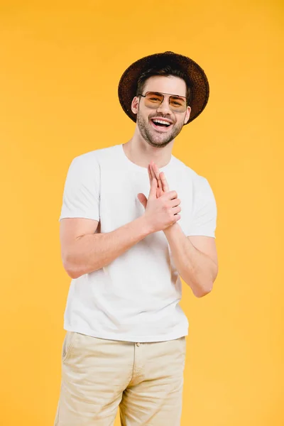 Beau jeune homme barbu en chapeau et lunettes de soleil souriant à la caméra isolé sur jaune — Photo de stock