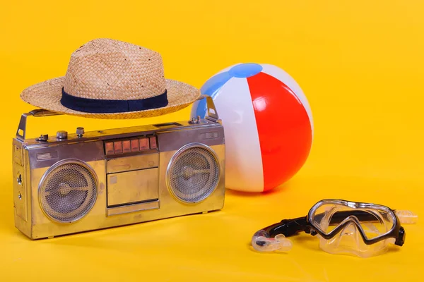 Grabadora de cinta, sombrero, pelota de playa y snorkel con máscara de buceo aislado en amarillo - foto de stock