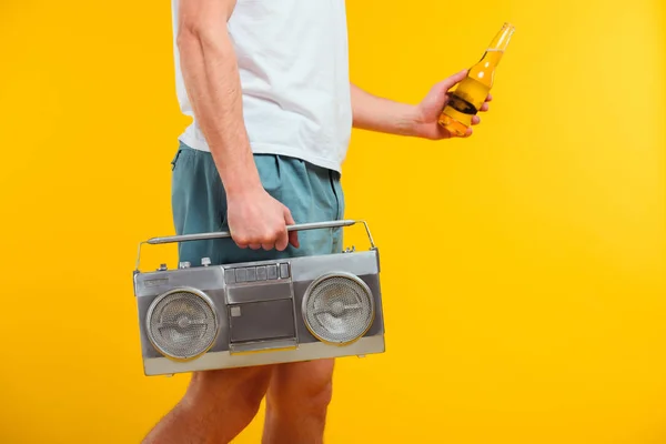 Cropped shot of man in shorts holding tape recorder and glass bottle of summer drink — Stock Photo