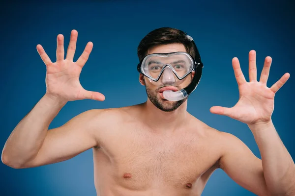 Весёлый молодой человек в маске для подводного плавания и подводного плавания жестом руками и взглядом в камеру на голубом — стоковое фото