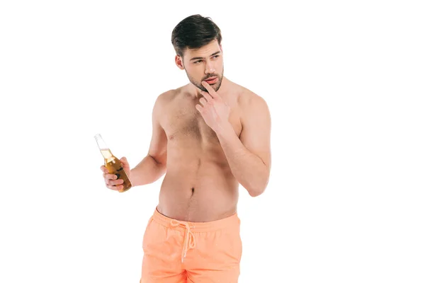 Schöner junger hemdloser Mann in kurzen Hosen, der eine Flasche Sommergetränk in der Hand hält und isoliert auf weißem Grund wegschaut — Stockfoto