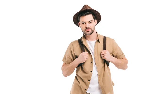 Guapo joven viajero en sombrero sosteniendo la mochila y mirando a la cámara aislada en blanco - foto de stock