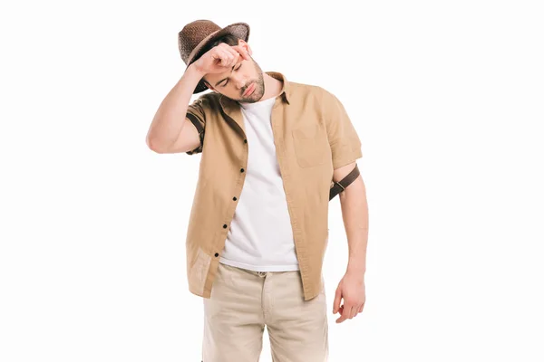 Tired young traveler in hat wiping sweat isolated on white — Stock Photo