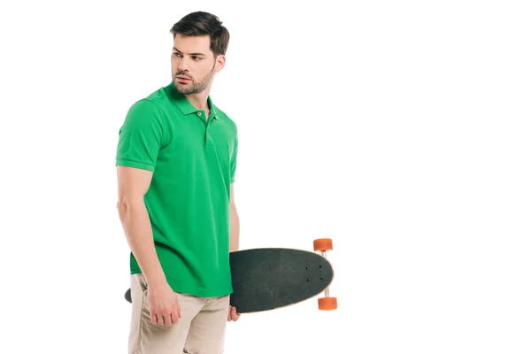 Jovem bonito segurando skate e olhando para longe isolado no branco — Fotografia de Stock