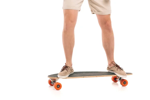 Sezione bassa di giovane uomo in pantaloncini in piedi su skateboard isolato su bianco — Foto stock