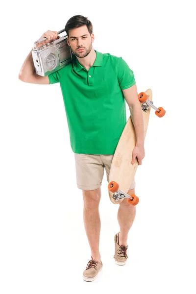 Jovem segurando skate e gravador de fita e olhando para a câmera isolada no branco — Fotografia de Stock