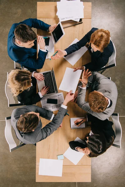 Vista superior de los empresarios que trabajan en la mesa con documentos, ordenador portátil, tableta y smartphone - foto de stock