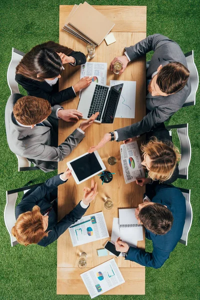 Top view of business colleagues working at table with laptop, smartphone and tablet in office — Stock Photo