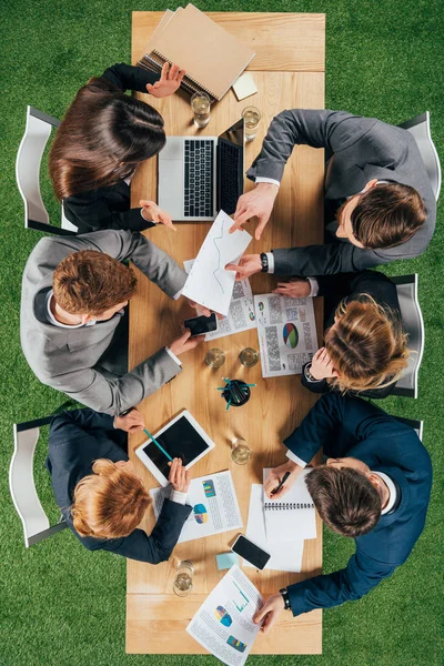 Overhead view of businesspeople having discussion at table with documents and devices in office — Stock Photo