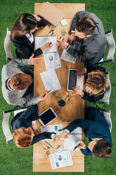 Overhead view of business colleagues having discussion at table with documents and devices in office — Stock Photo