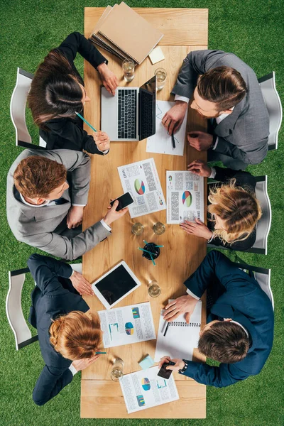Overhead view of business partners having discussion at table with documents and devices in office — Stock Photo