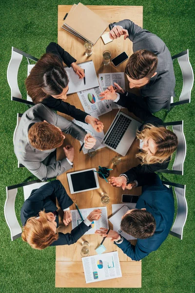 Overhead view of angry business partners having discussion at table with documents and devices in office — Stock Photo