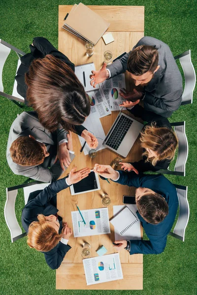 Overhead view of angry business partners having discussion at table with documents and devices in office — Stock Photo