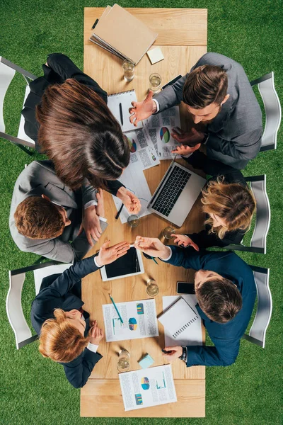 Overhead-Ansicht wütender Geschäftspartner, die mit Dokumenten und Geräten im Büro am Tisch diskutieren — Stockfoto