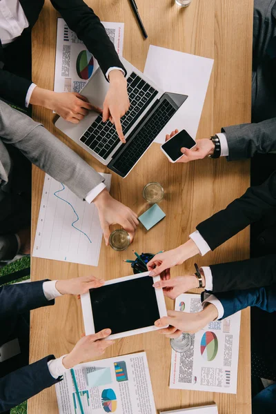 Vista recortada de socios comerciales compartiendo tableta digital en la mesa en la oficina - foto de stock