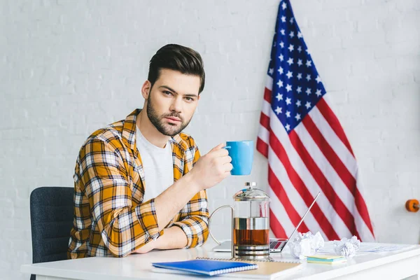 Jungunternehmer arbeitet am Laptop und trinkt Kaffee — Stockfoto