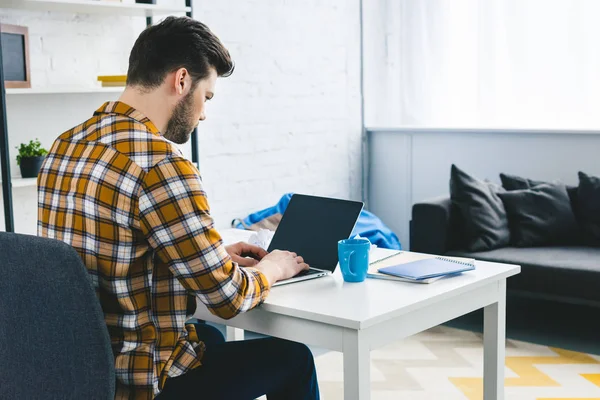 Uomo che lavora da tavolo con computer portatile in ufficio leggero — Foto stock