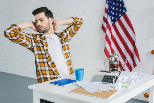 Tired freelancer stretching by working table in light office — Stock Photo
