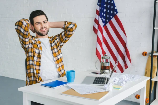 Freelancer relaxing during break by table with laptop at home office — Stock Photo