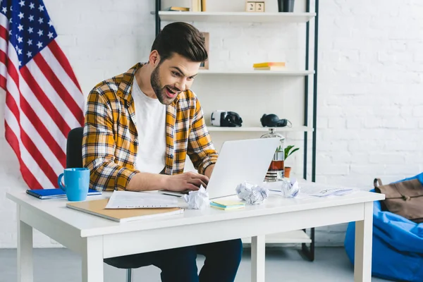 Sorrindo homem olhando para a tela do laptop no escritório leve — Fotografia de Stock