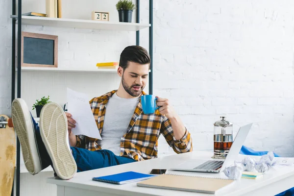 Homme d'affaires tenant du papier et buvant du café au bureau à domicile — Photo de stock