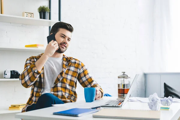 Homme d'affaires assis à table et parlant au téléphone au bureau à la maison — Photo de stock