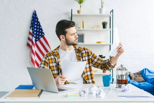 Uomo d'affari che studia i documenti mentre lavora con il computer portatile a casa ufficio — Foto stock