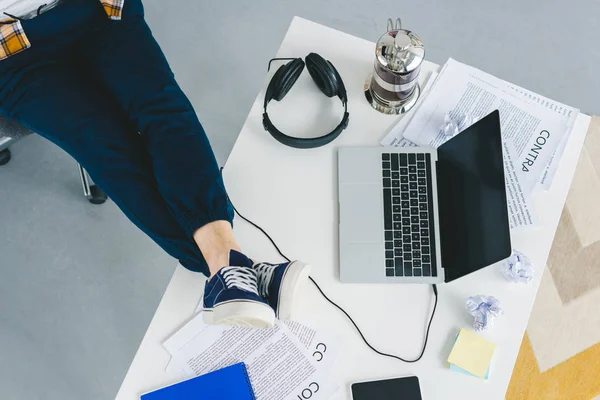 Крупним планом вид чоловічих ніг на столі з ноутбуком у світлому офісі — стокове фото
