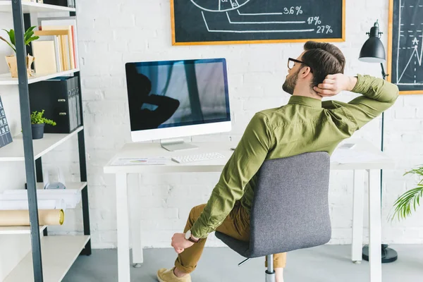 Tired freelancer stretching by working table in light office — Stock Photo