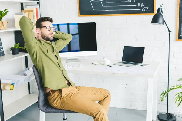 Empresário cansado que estica pela mesa de trabalho no escritório home — Fotografia de Stock